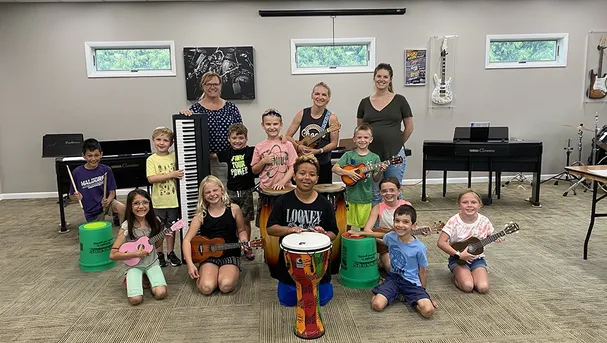 Students listening to a camp instructor in front of their pianos.